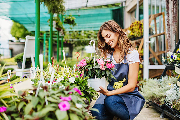 In the garden center Attractive young woman working in a garden center. green fingers stock pictures, royalty-free photos & images