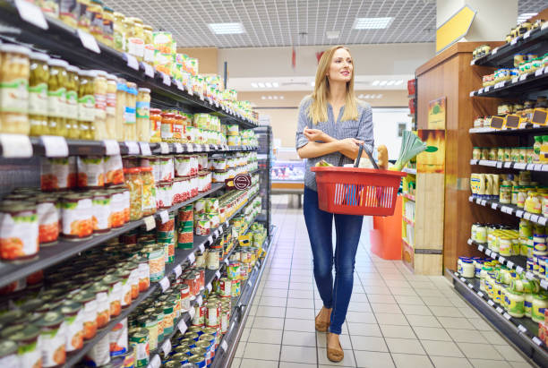 Woman is looking around in grocery store Woman is looking around in grocery store holding shopping basket stock pictures, royalty-free photos & images