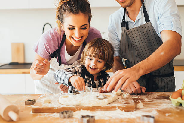 Family making cookies in the kitchen Young happy family making cookies in the kitchen. flour mess stock pictures, royalty-free photos & images