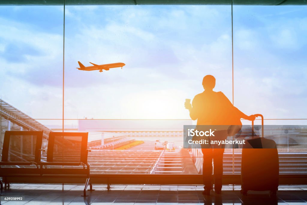 happy traveler waiting for the flight in airport happy traveler waiting for the flight in airport, departure terminal, immigration concept Airport Stock Photo