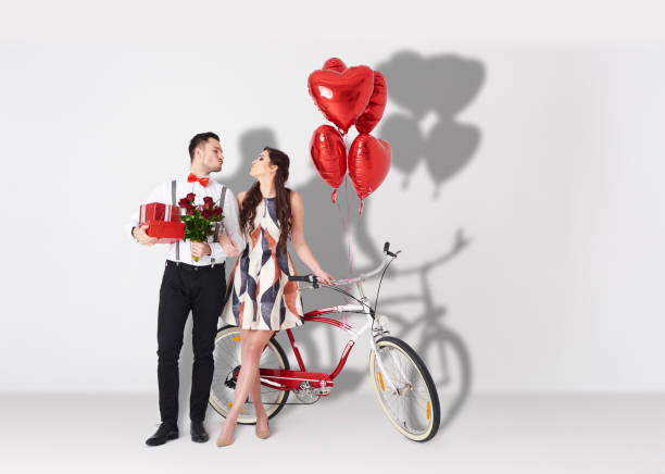 couple joyeux avec accessoires de saint-valentin - men giving balloon women photos et images de collection