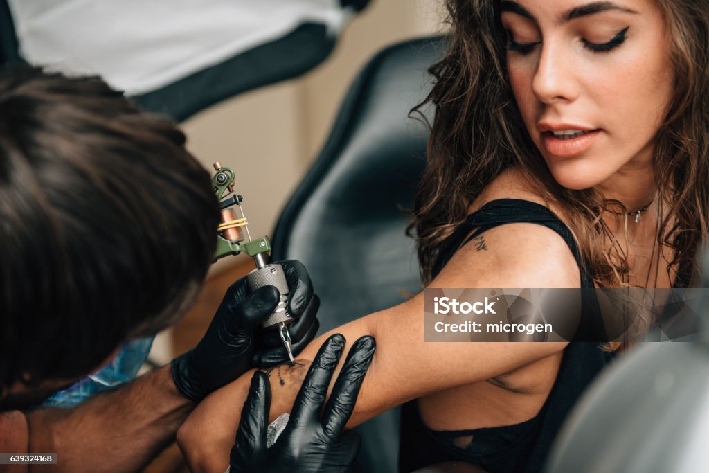 Tattoo Tattoo. Pretty girl getting a tattoo. Toned image Tattoo Stock Photo