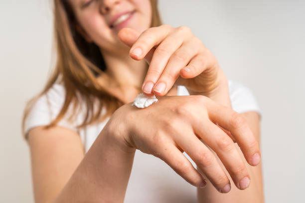 istock Smiling young woman applying cream on her hands 639324926