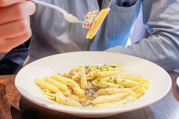 istock Young man eating carbonara pasta 639325752