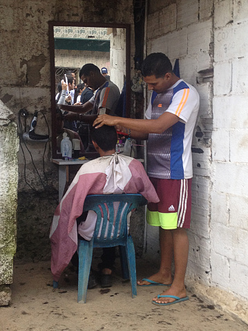 Caracas, DF, Venezuela – November 19, 2016:A man getting his haircut outdoors in a poor neighborhood in Caracas, Venezuela.
