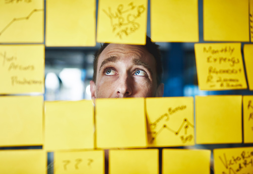 Shot of a young man having a brainstorming session with sticky notes at work