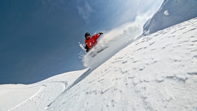 SPEED RAMP Backcountry snowboarder splashing powder snow into the camera