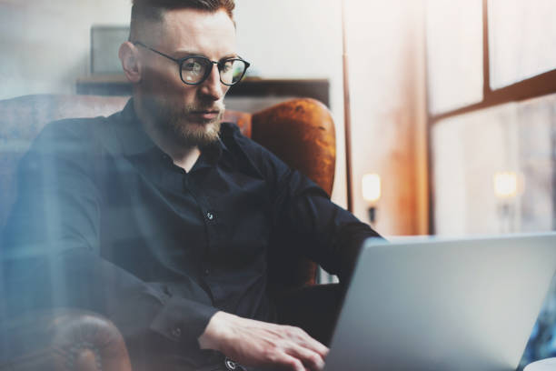 istock Bearded young businessman working in modern loft office. Man using 639356330