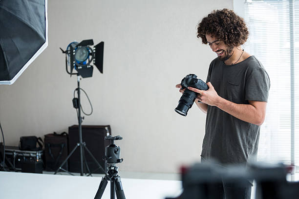fotógrafo masculino revisando fotos capturadas en su cámara digital - professional photographer fotografías e imágenes de stock