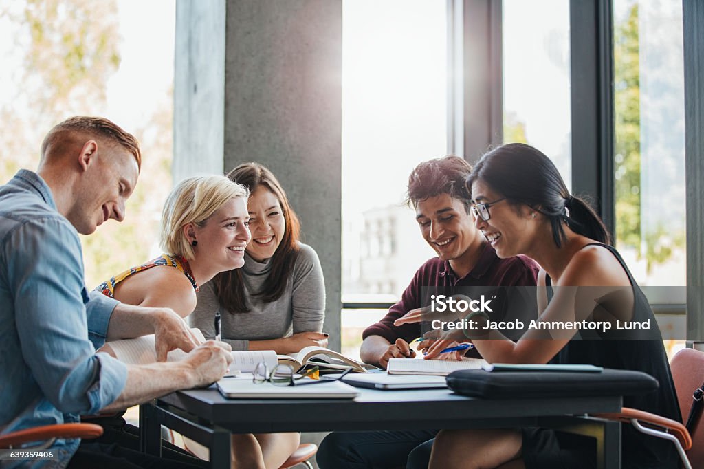 Studenti che studiano nella biblioteca universitaria - Foto stock royalty-free di Gruppo di persone