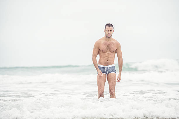 海で灰色の水泳ショートパンツを着ている男。 - swimming shorts ストックフォトと画像