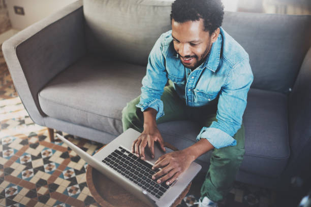istock Smiling bearded African man working notebook at home while sitting 639371240