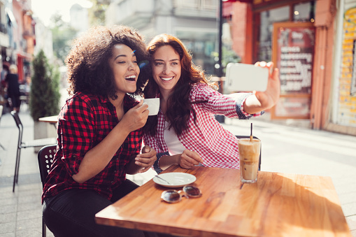 Beautiful girls at sidewalk cafe taking selfie together