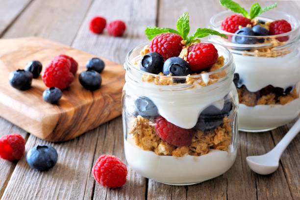 istock Blueberry, raspberry parfaits in mason jars, still life over wood 639375856