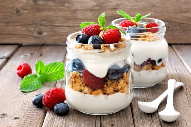 Blueberry, raspberry parfaits in mason jars, still life against wood stock photo