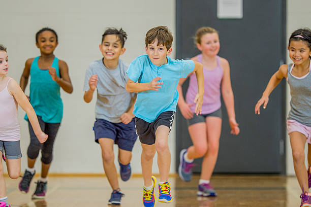 Exercising as a Class An elementary age Caucasian boy runs at the front of the group during gym class. physical education stock pictures, royalty-free photos & images