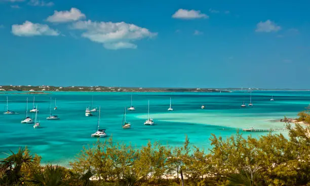 many sailboats and power boats anchored in crystal clear turquoise waters of the bahamas.  copy space available.