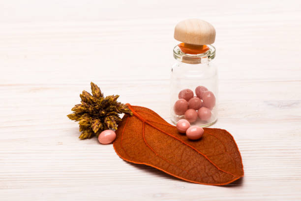 Pink pills with orange leaf on wooden table stock photo
