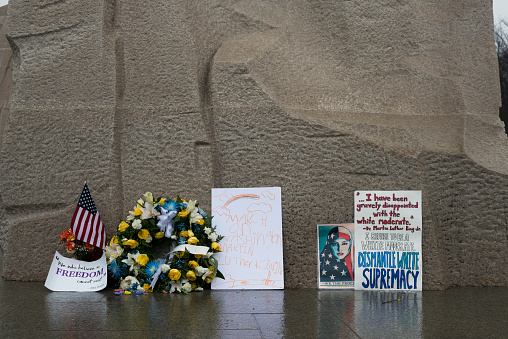 Washington DC, USA - January 22, 2017: A collection of signs, flowers, and an American flag, left on a rainy afternoon at the base of the Martin Luther King Jr. Memorial in Washington DC.