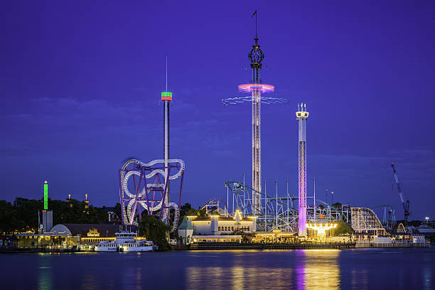 Theme park rides roller coasters illuminated Grona Lund Stockholm Sweden Stockholm, Sweden - July 7, 2016: View across the blue waters of Riddarfjarden to the rollercoasters and fairground rides of Tivoli Gruna Lund amusement park illuminated at night on Djurgarden in central Stockholm, Sweden's picturesque capital city.  djurgarden photos stock pictures, royalty-free photos & images