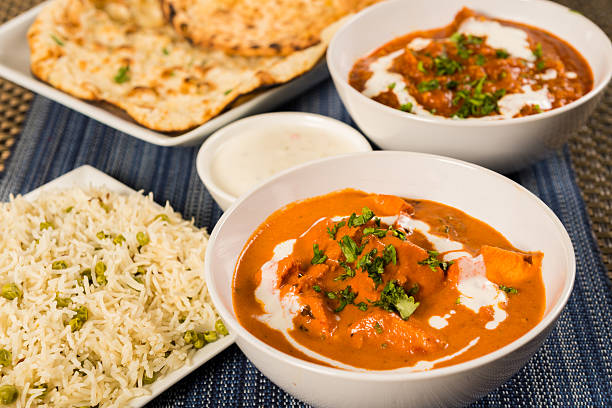 Authentic Indian Food Butter chicken curry, lamb vindaloo, basmati rice, nan bread and yoghurt raita indian food stock pictures, royalty-free photos & images