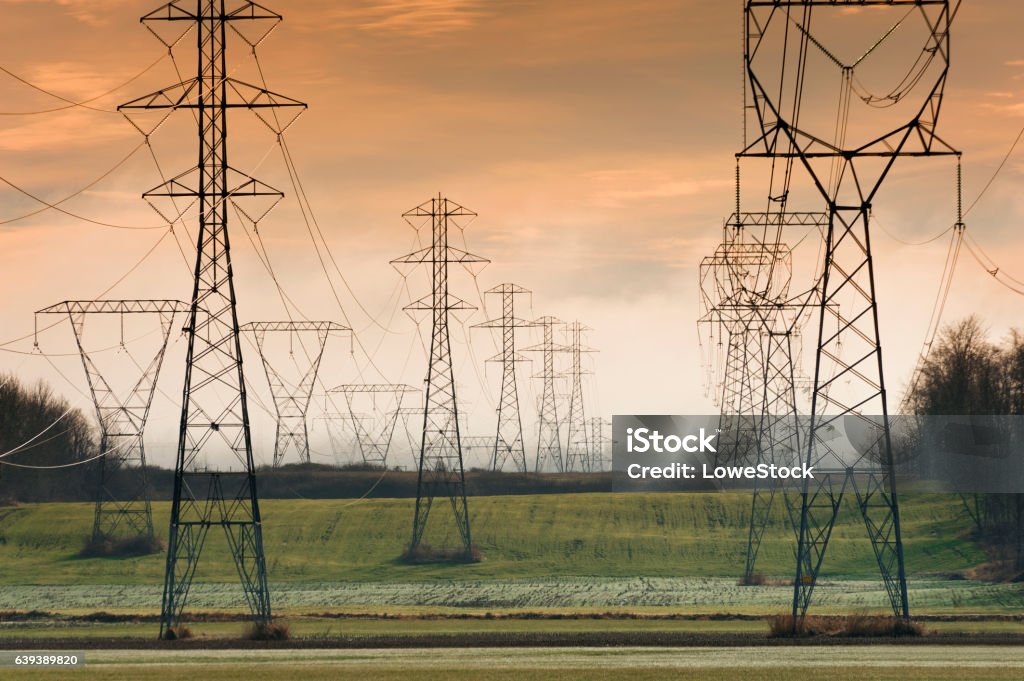 High Tension Power Lines During a lovely sunset high tension power lines run across the rural landscape bringing electrical power to the area. Power Cable Stock Photo