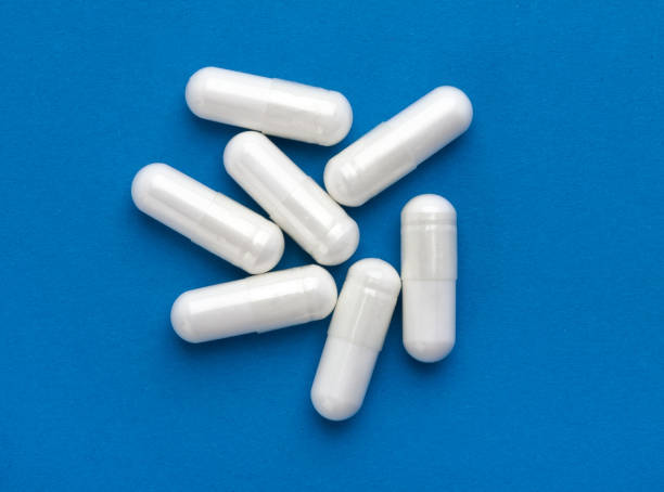 Several white medicine capsules stock photo