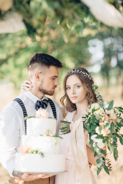 istock bride and groom holding a wedding cake 639394076