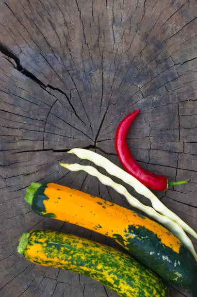 Photo of green-orange zucchini, pods of white beans and red chilli