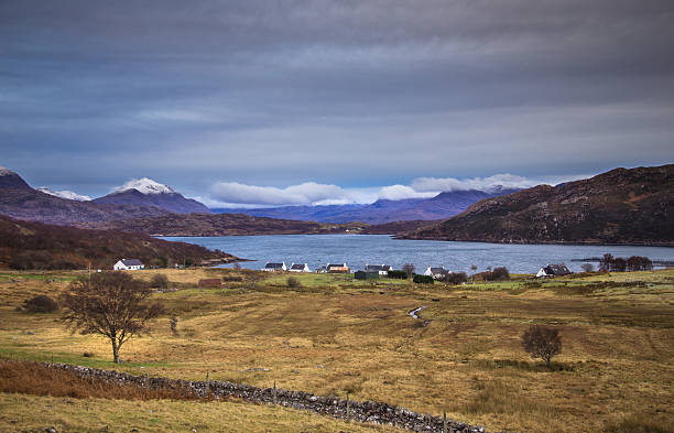 Arrina, Applecross Peninsula, Scottish Highlands View down a slope to the small hamlet of Arrina, on the Applecross Peninsula in the Scottish Highlands. In the water of the loch several boats are bobbing on the edge of large salmon hatcheries. The trees are bare, the grass is brown and the mountains are capped with snow on a cold winter day. applecross peninsula stock pictures, royalty-free photos & images