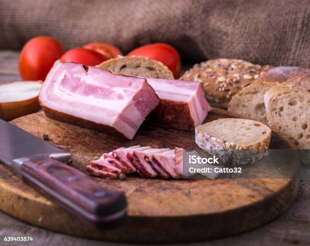 Raw Bacon On Old Cutting Board With Bread And Tomatoes Stock Photo - Download Image Now