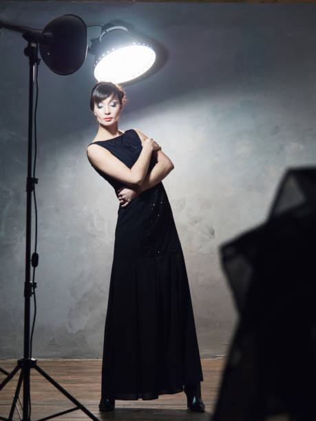 istock Young girl in evening dresses on grey wall. 639404458
