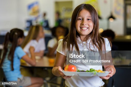 istock Happy elementary school girl with healthy food in cafeteria 639407344