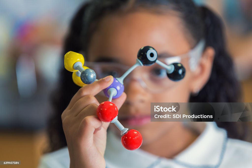 Niña que sostiene un modelo de estructura molecular - Foto de stock de Educación en escuela privada libre de derechos