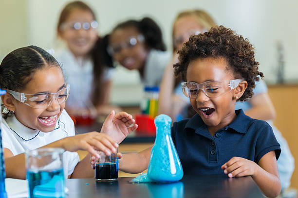 aufgeregte schulmädchen beim chemieexperiment - grundschüler stock-fotos und bilder