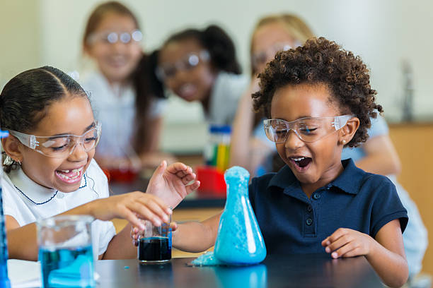 excited school girls during chemistry experiment - basisschool stockfoto's en -beelden