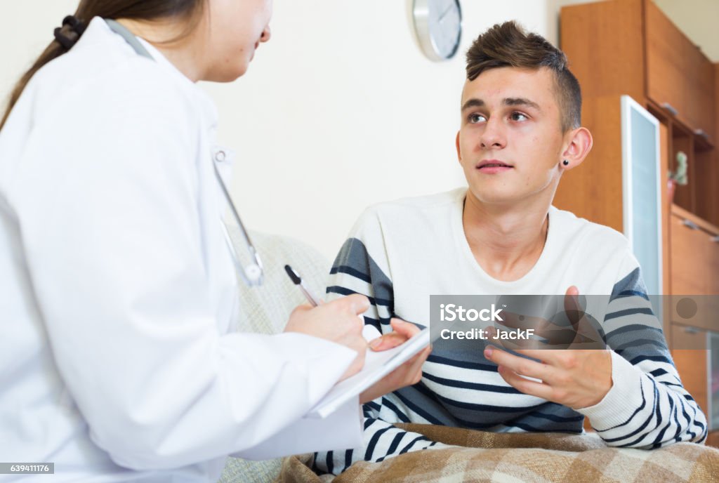 Médico examinating teen boy with quinsy en su casa - Foto de stock de Adolescente libre de derechos