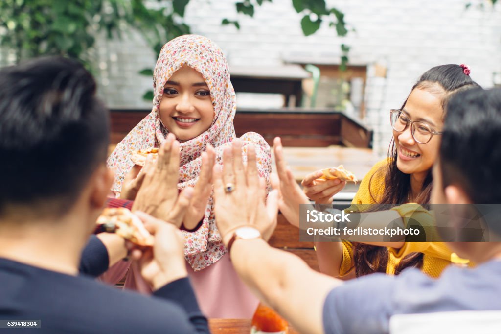 friend giving high five at cafe portrait of asian friend giving high five at cafe while having a lunch Teenager Stock Photo