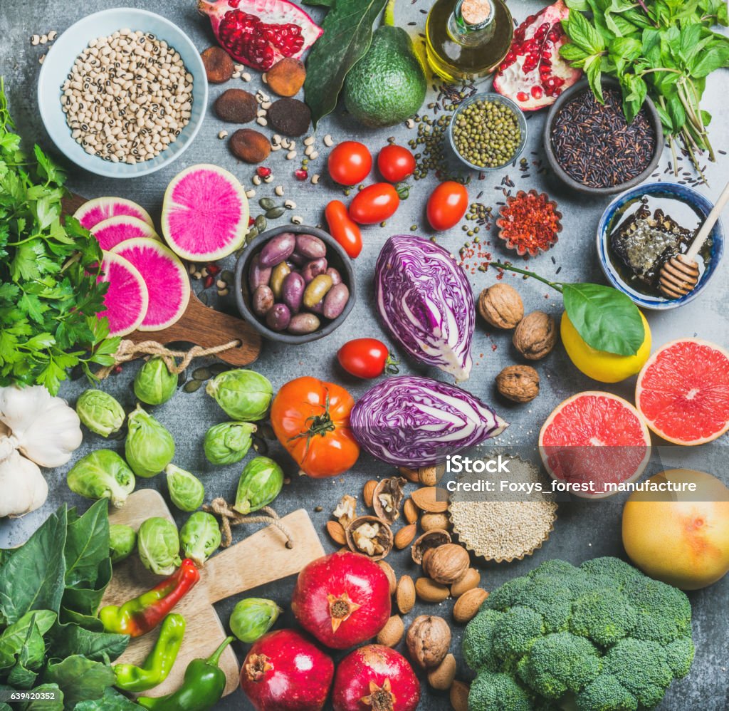 Healthy raw food variety over grey concrete background Clean eating concept over grey concrete background, top view. Vegetables, fruit, seeds, cereals, beans, spices, superfoods, herbs for vegan, gluten free, allergy-friendly weight loosing or raw diet Food Stock Photo