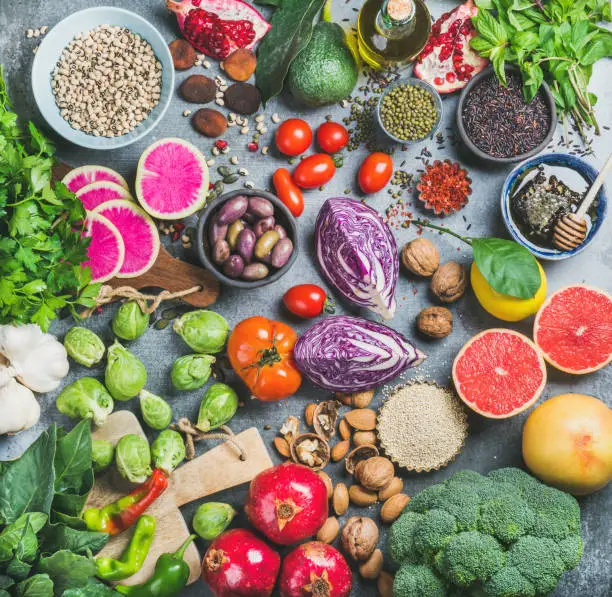 Clean eating concept over grey concrete background, top view. Vegetables, fruit, seeds, cereals, beans, spices, superfoods, herbs for vegan, gluten free, allergy-friendly weight loosing or raw diet