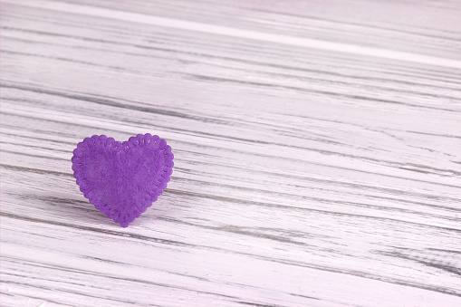 Purple felt heart on a white wooden background. Valentine Day.Greeting card.Wedding