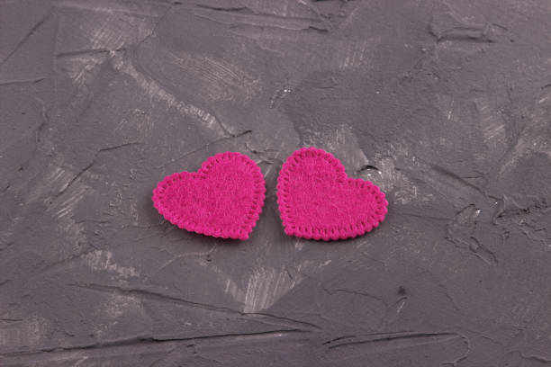 Two hearts of felt on the dark concrete background Two hearts of felt on the dark concrete background. Valentine Day.Greeting card.Wedding felt heart shape small red stock pictures, royalty-free photos & images