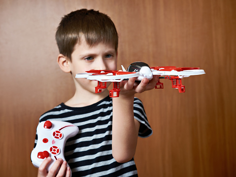 Little boy with toy quadcopter drone at home