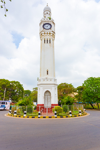 Jaffna, Sri Lanka - February 3, 2015: Bus driving around a British colonial style roundabout at the central landmark clock tower on an overcast day in downtown
