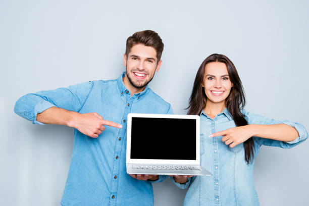 istock Happy couple showing laptop and pointing on black screen 639425764