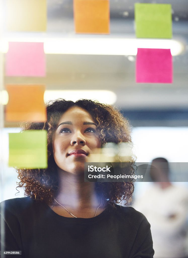 Thinking critically to create success Shot of a young woman having a brainstorming session with sticky notes at work Planning Stock Photo