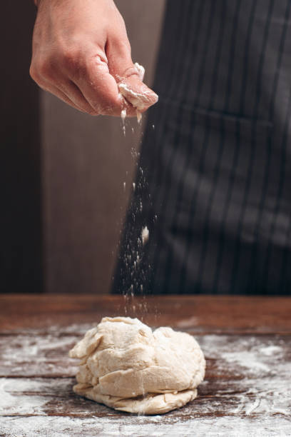 istock Baker sprinkling flour above raw dough 639433706