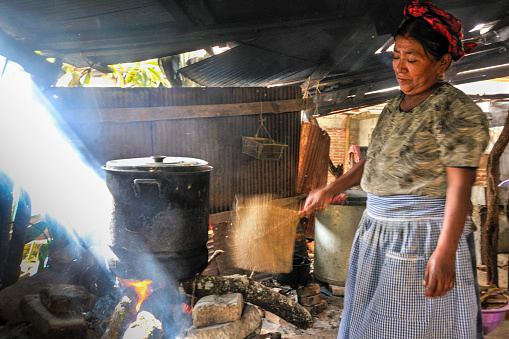 Teotitlán, Oaxaca, Mexico- October 29, 2009: A woman making tamales over a fire in a huge cooking pot.