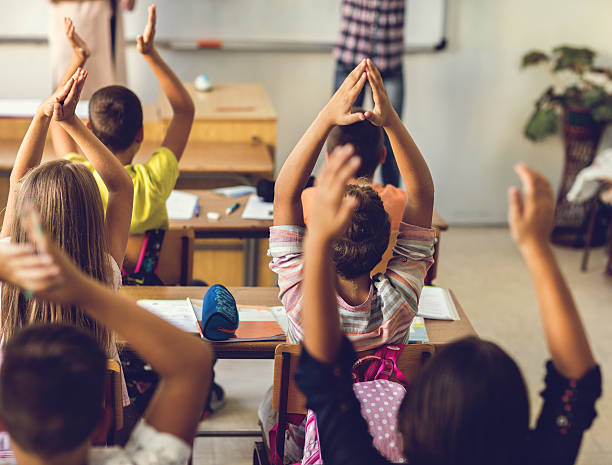 istock Rear view of school kids clapping hands in the classroom. 639439266