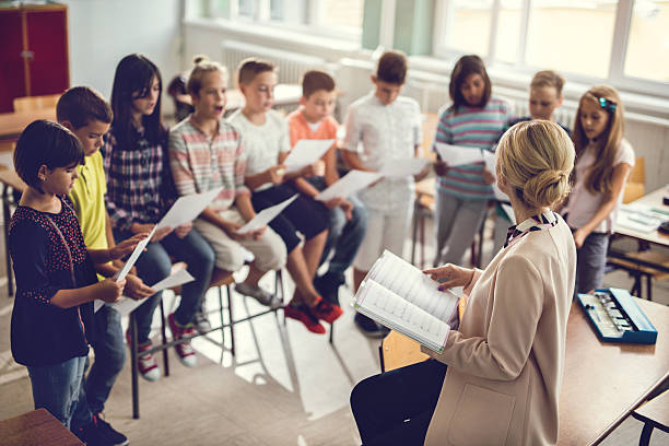 elementary school teacher singing with children in the classroom. - singing lesson imagens e fotografias de stock